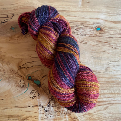 a skein of handspun yarn with red, orange, and dark green