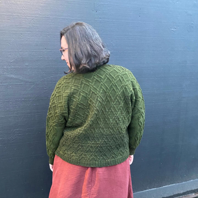 a back view of a dark green cabled cardigan